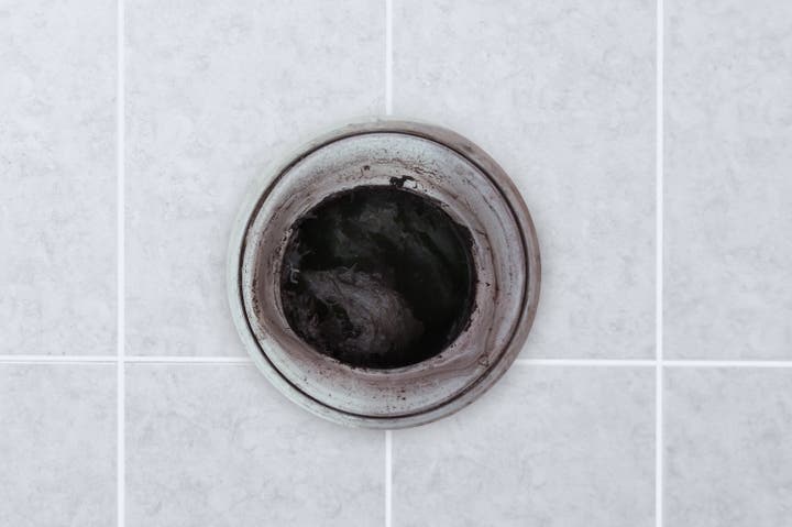 A Servpro technician is unclogging a dirty kitchen drain. The image shows the technician using specialized tools to clear the blockage and restore proper drainage. The scene emphasizes the importance of professional plumbing services in maintaining a clean and functional kitchen sink