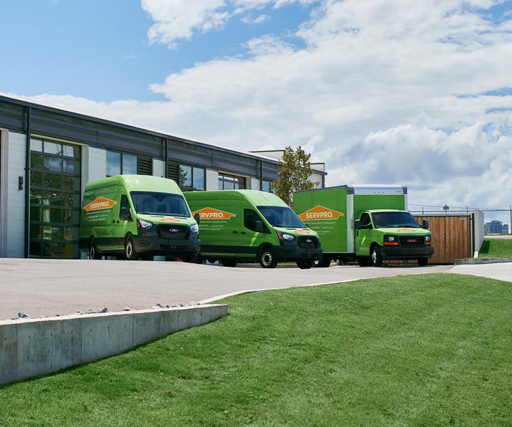 2 SERVPRO vans and a SERVPRO truck parked by a building waiting to serve your commercial business needs